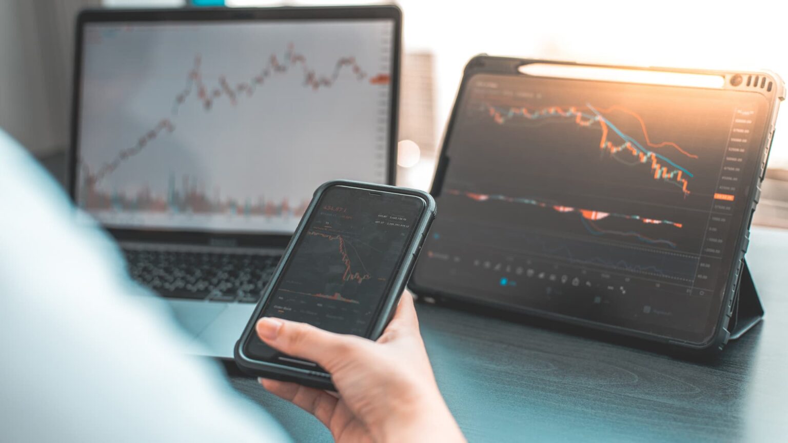 Computer tablet and phone showing stock market numbers